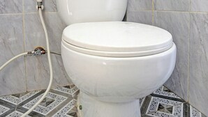 A toilet with a marble wall and tiled floor. - OYO 92541 Suny Kost Syariah (Sidoarjo)