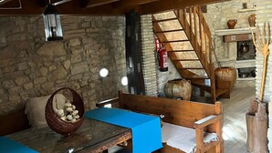 A rustic dining area with a wooden table and benches, stone walls, and a staircase leading upstairs. - Masia CAN Tronc Casa Rural Tranquila,disfrutar en la Naturaleza en Familia (BARCELONA)