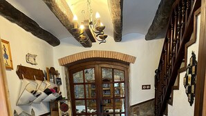 A hallway with a wooden door, a tiled floor, and a chandelier. - Masia CAN Tronc Casa Rural Tranquila,disfrutar en la Naturaleza en Familia (BARCELONA)