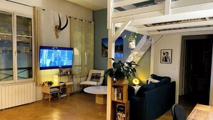 A living room with a TV, sofa, and staircase. - Appartement Design Proche Paris & Versailles (Meudon)