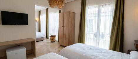 A hotel room with two beds, a TV, a minibar, a wooden wardrobe, and a wicker chandelier.