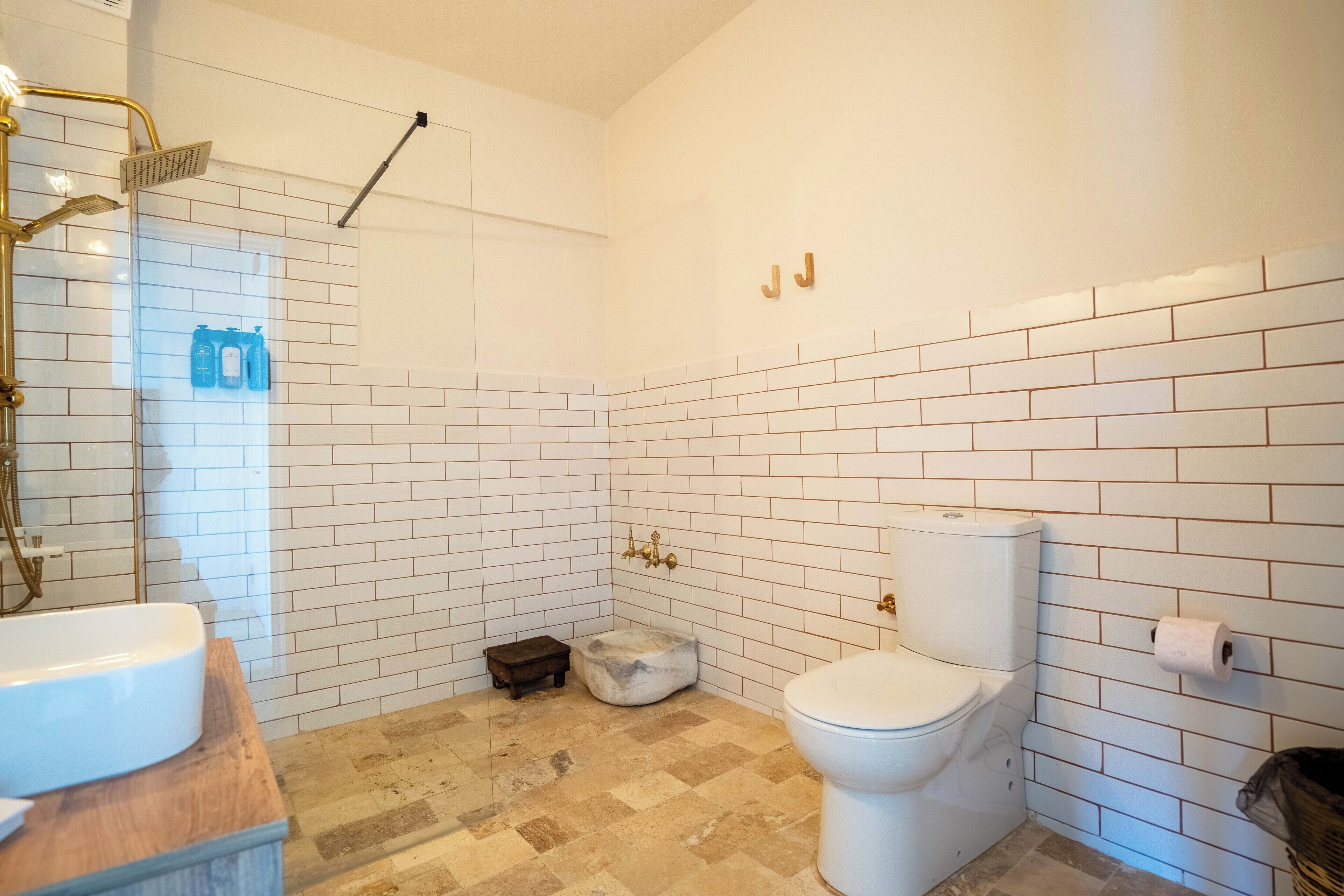 Un baño con lavamanos, inodoro y zona de ducha blanca.