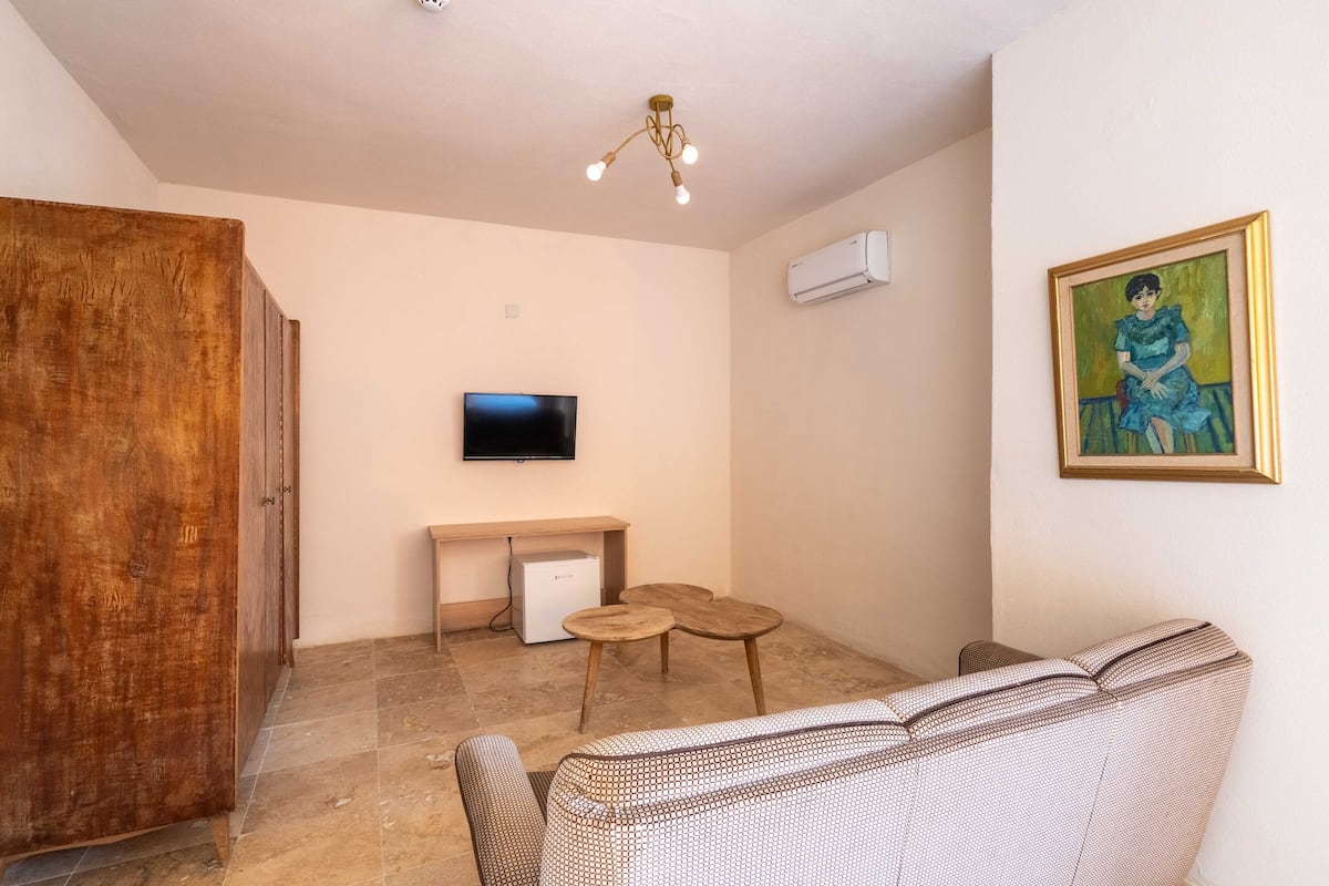 A living room with a sofa, a TV, a small table, a wooden cabinet, and a painting on the wall.