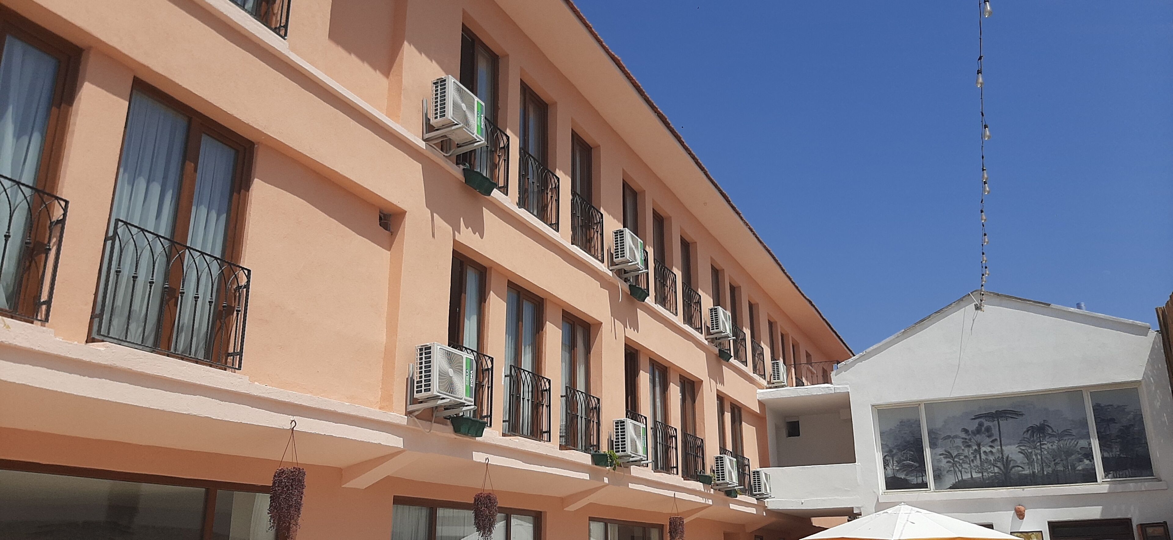 A multi-story building with balconies, air conditioning units, and hanging plants.