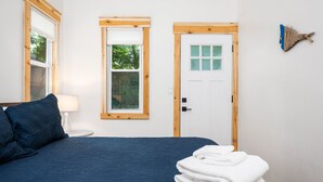 A bedroom with a bed, a window, a door, and a wall-mounted object. - Hot Tub| Sauna| Arbutus Lake| Pines| 15 min to TC! (Traverse City)