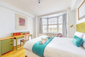 Relax in a spacious room with a large bed, desk, and window with blinds.