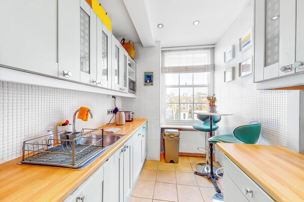 Enjoy cooking in this well-lit kitchen with a dishwasher, sink, and window offering a city view.