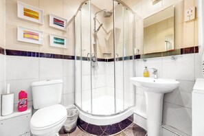 Enjoy a refreshing shower in the bathroom, featuring a glass-enclosed shower area, a toilet, and a pedestal sink.