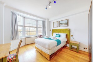 Relax in a serene space with a large bed, nightstand, and comfortable chair.