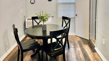 A dining area with a round table, four chairs, a small potted plant, and two hexagonal wall decorations.