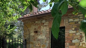 Un bâtiment rustique en pierre, doté d’un portail en métal, d’une petite entrée et d’un toit en briques.