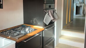Une cuisine moderne avec des meubles de couleur noire, une hotte de cuisine en acier inoxydable, une cuisinière à gaz et un four encastré.