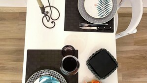 Une table à manger dressée avec des assiettes, des couverts, des verres et une bougie.