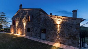Une maison en pierre dotée d’un éclairage extérieur soigné et d’un chemin pavé menant à l’entrée.