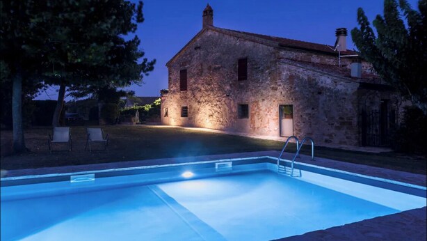 Un bâtiment en pierre avec une piscine devant.