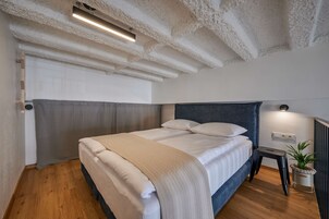 Een slaapkamer met een bed, nachtkastje en een potplant.