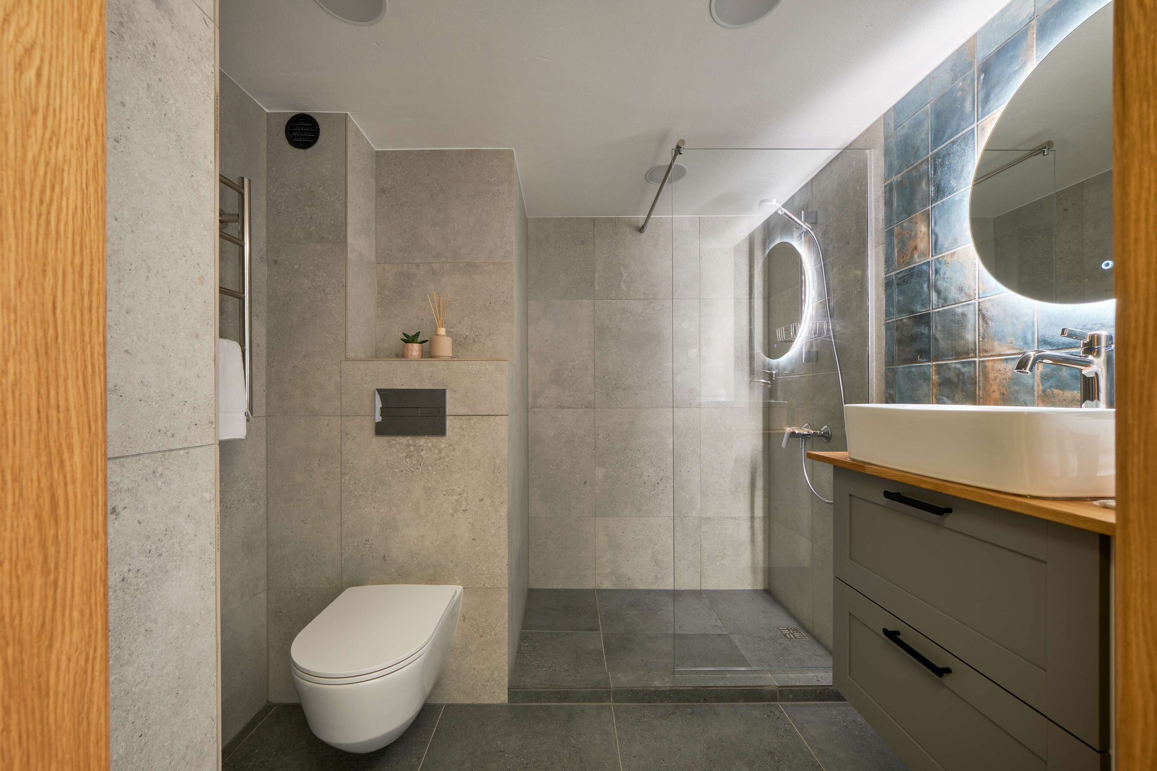 Un baño moderno con inodoro, ducha y tocador con espejo.