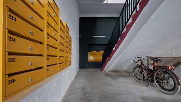 A hallway with numbered yellow mailboxes and a bicycle parked near a staircase.