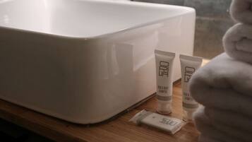 Un bany amb un lavabo blanc, un mirall rodó i productes de tocador al taulell.