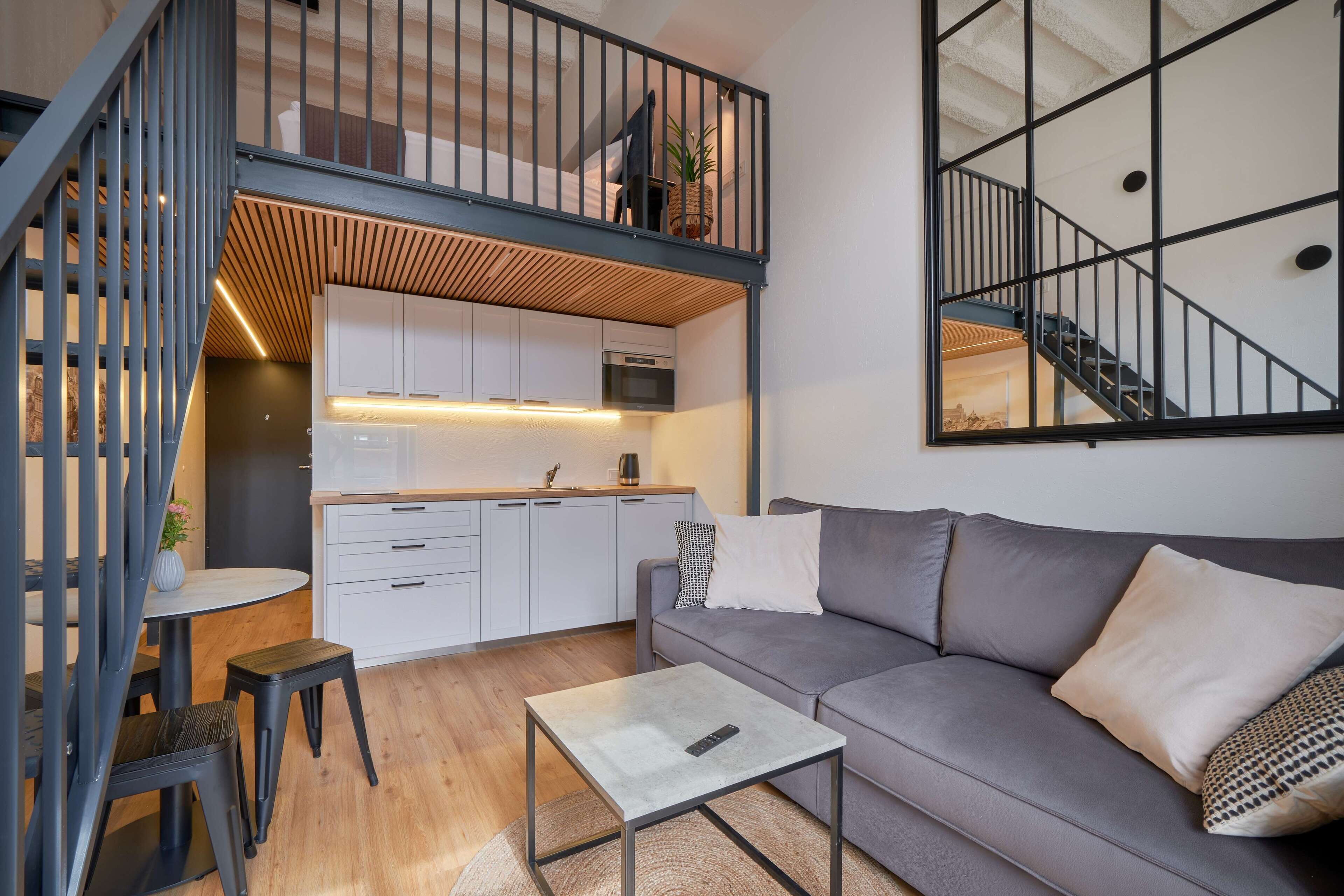 A modern apartment with a loft bedroom, kitchen, and living area.