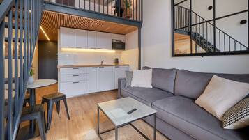 A modern apartment with a loft bedroom, kitchen, and living area.