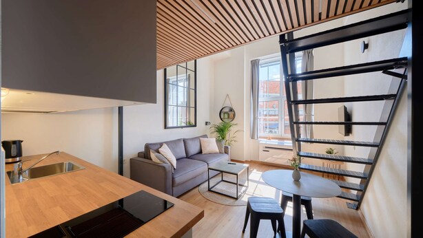 A modern kitchen with a wooden countertop, a built-in dishwasher, and a sink. - Queen Barbora Central Lofts (Kaunas)