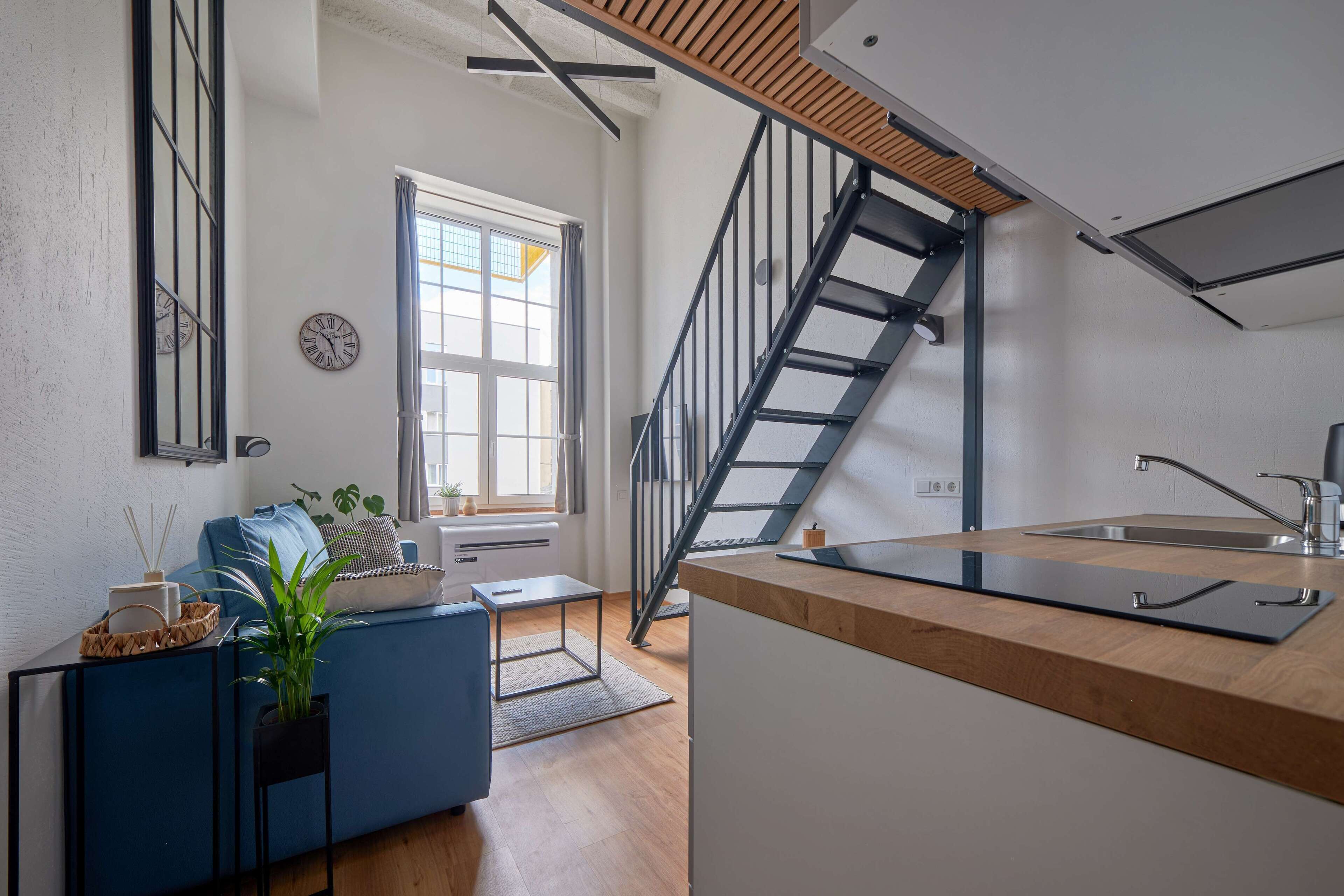 Una cocina moderna con encimera de madera, pileta integrada y una escalera que sube a un nivel superior.