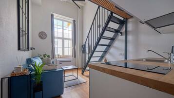 Una cocina moderna con encimera de madera, pileta integrada y una escalera que sube a un nivel superior.