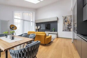 Una sala moderna con una mesa de comedor de madera, un sofá y un televisor montado en la pared.