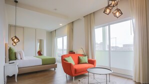 Una habitación de hotel moderna con una cama, un sofá, una mesita y ventanas amplias.