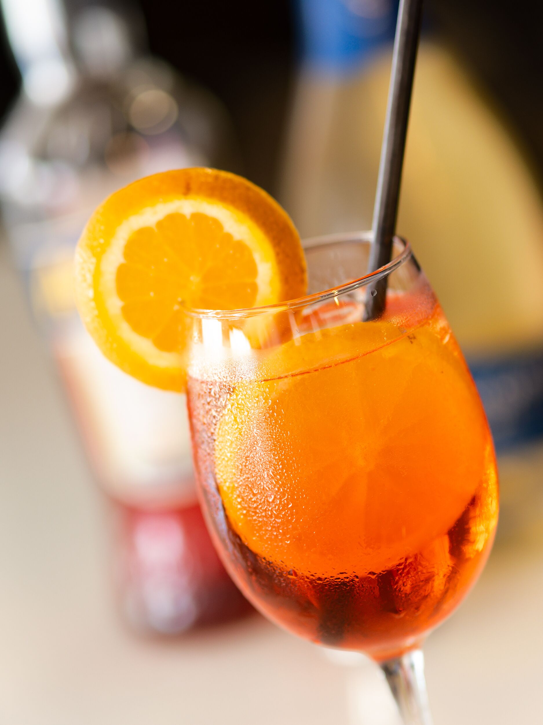 Primer plano de un vaso con una bebida y una rodaja de naranja como adorno.
