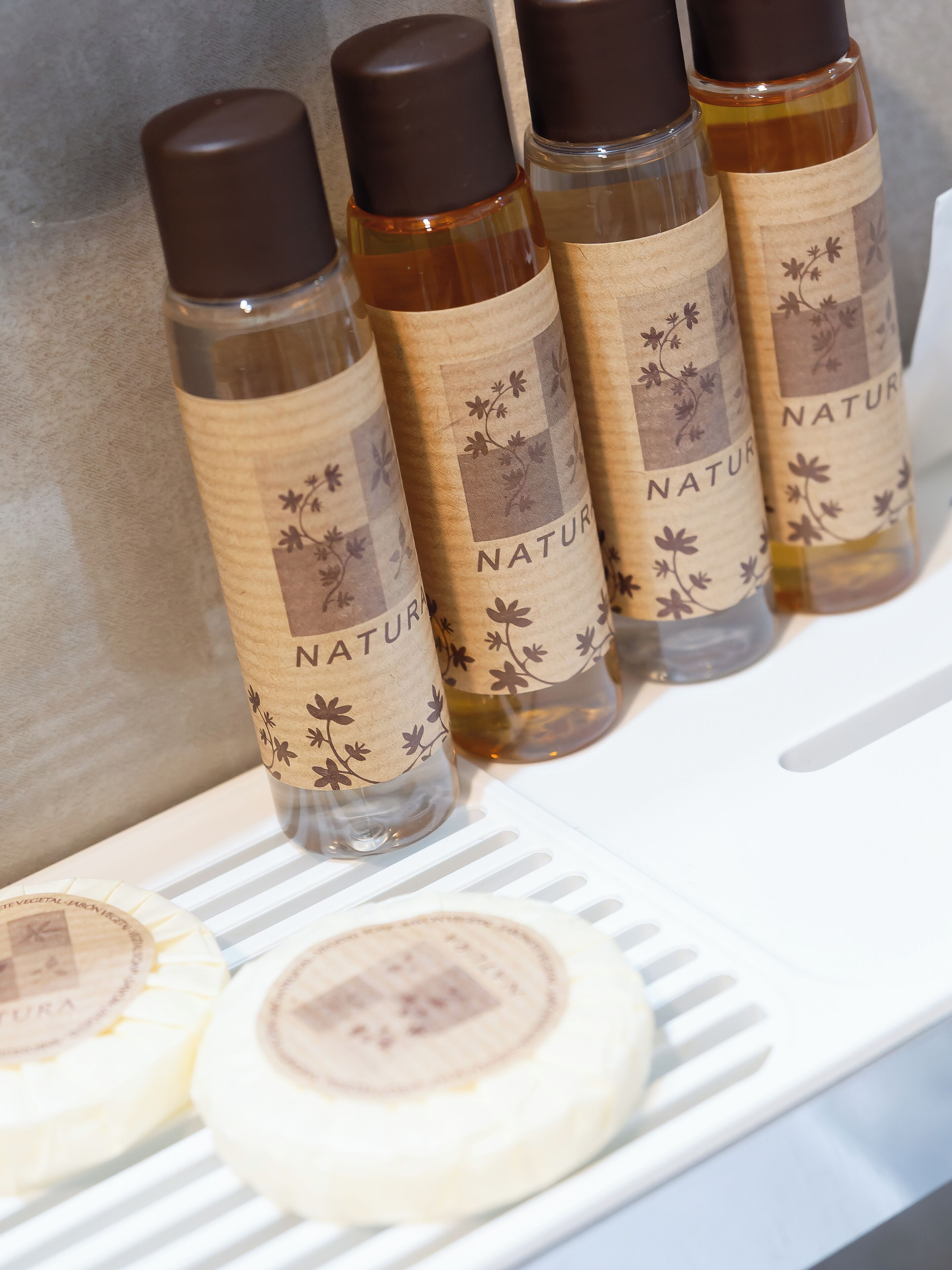 Una estantería con botellas etiquetadas 'NATUR' y unos cuantos recipientes redondos.