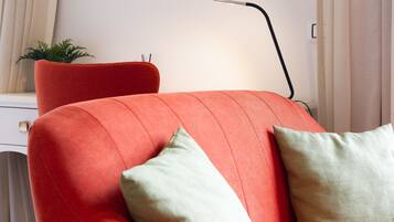 Un salon moderne avec un canapé rouge, une lampe sur pied et une petite plante.