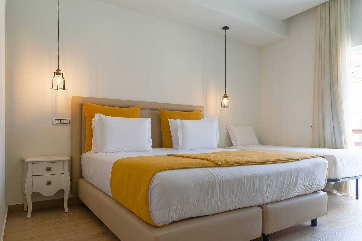 Un dormitorio moderno con una cama grande, mesitas de noche e iluminación colgante.