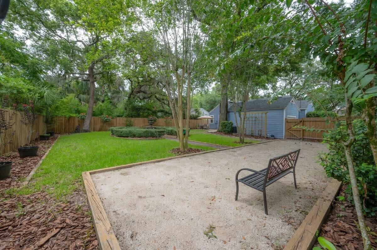 A backyard with a bench, a wooden fence, and a house in the background.