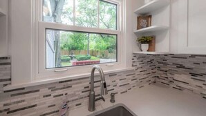 A kitchen with a window, a sink, and a tiled backsplash.