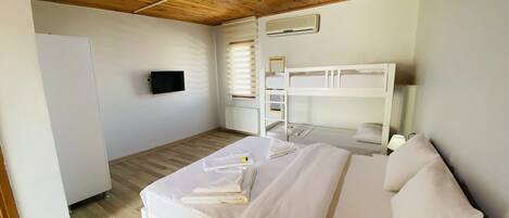 A bedroom with a bunk bed, a flat-screen TV, a heater, and a window with blinds.
