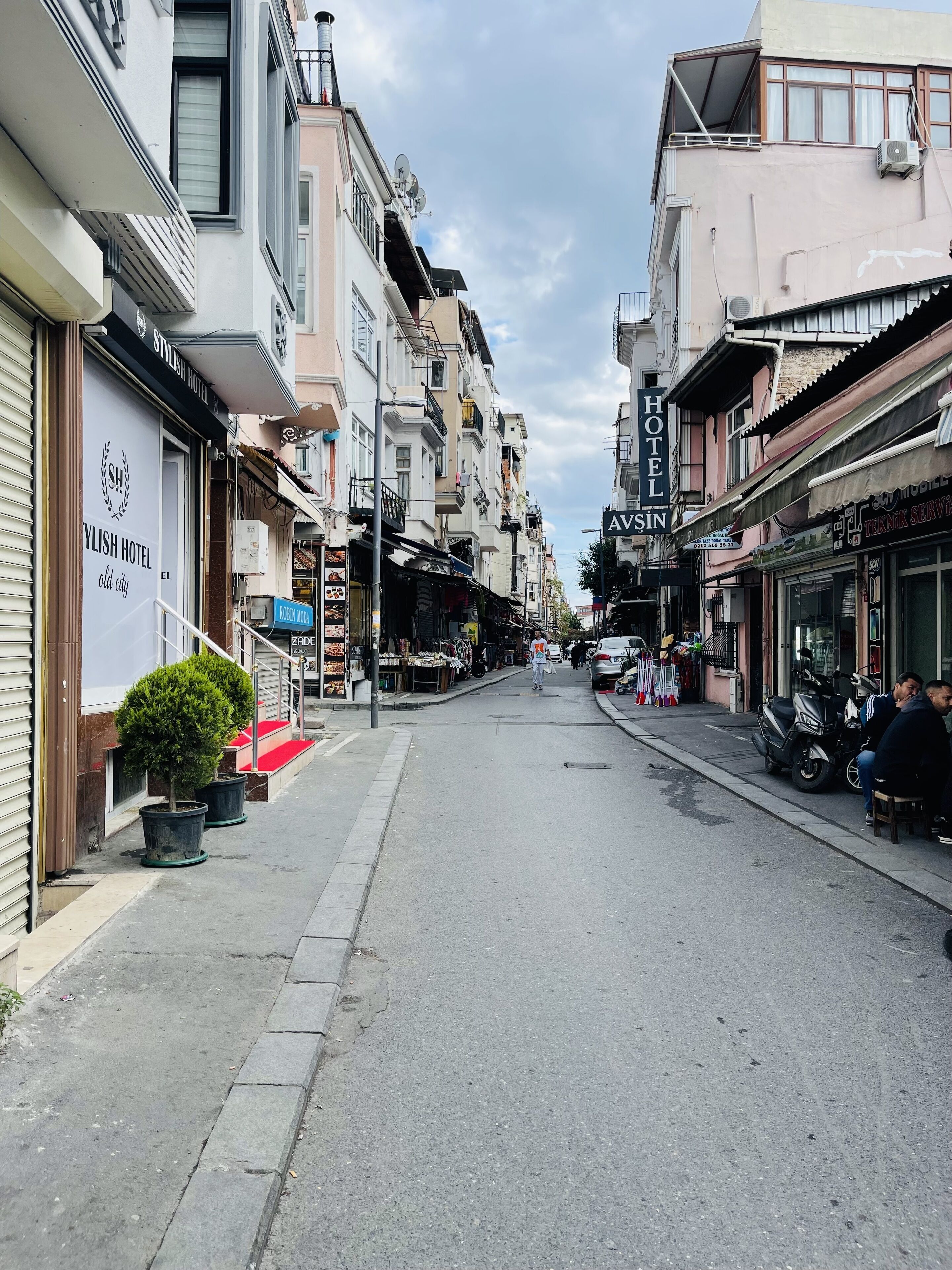 A street lined with multi-story buildings, including a hotel and various shops.