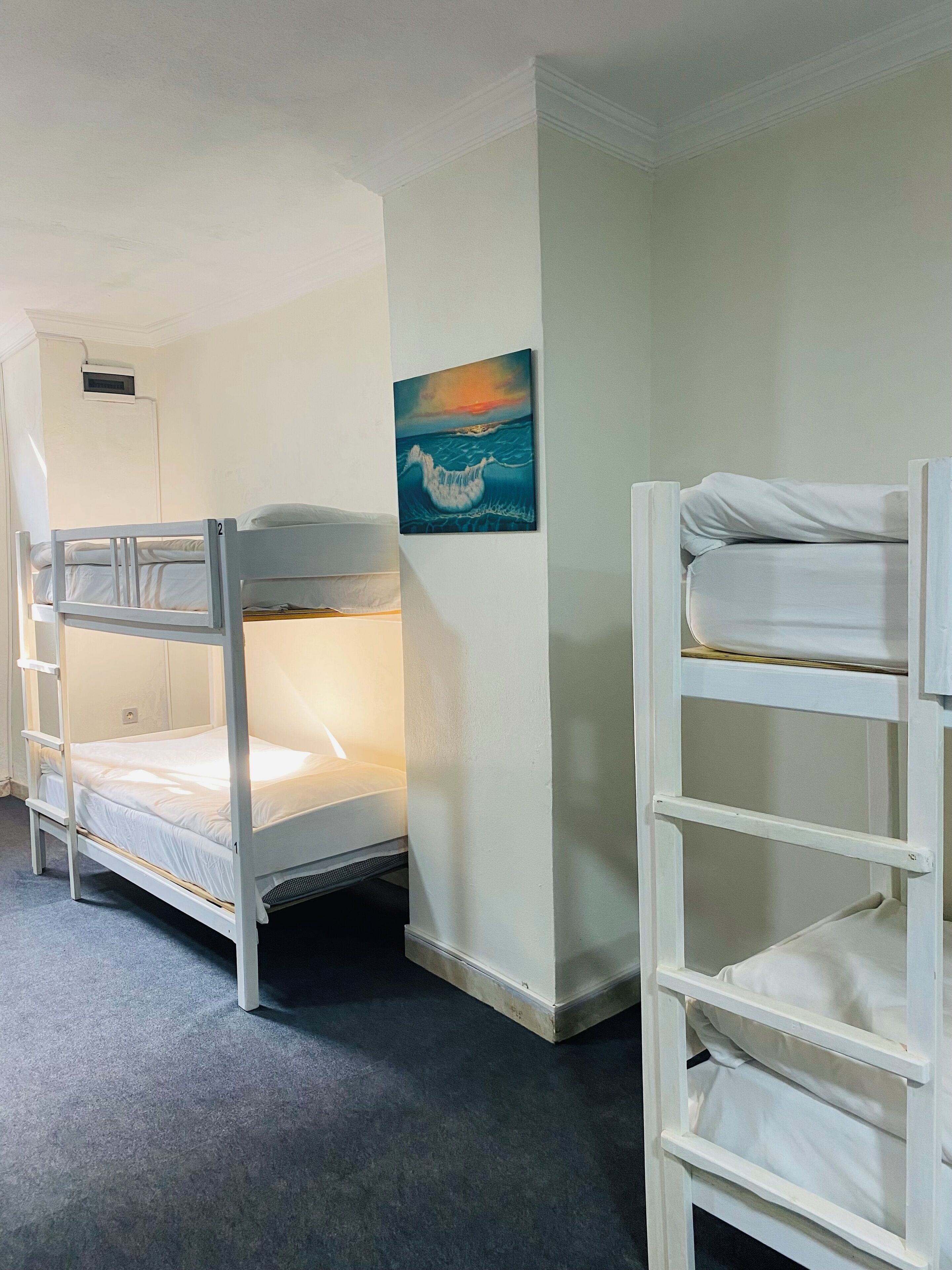A bunk bed room with a painting of a wave on the wall.