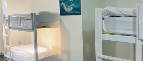A bunk bed room with a painting of a wave on the wall.