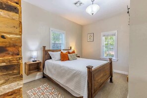 Ein Schlafzimmer mit einem Holzbett, zwei Nachttischen, einem Beistelltisch und einem gemusterten Teppich.