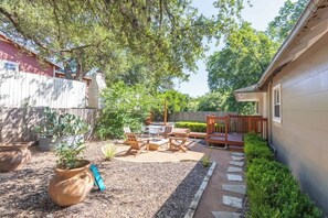 A backyard with a patio, seating area, and potted plants.