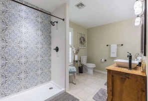 A bathroom with patterned tiles, a wooden vanity, a white sink, and a toilet.