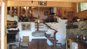 A rustic interior with a wooden staircase, a fireplace, and a dining table. - Chalet de Bébert (Conthey)