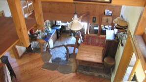 A rustic kitchen with wooden beams, a hanging light fixture, and a stone hearth. - Chalet de Bébert (Conthey)