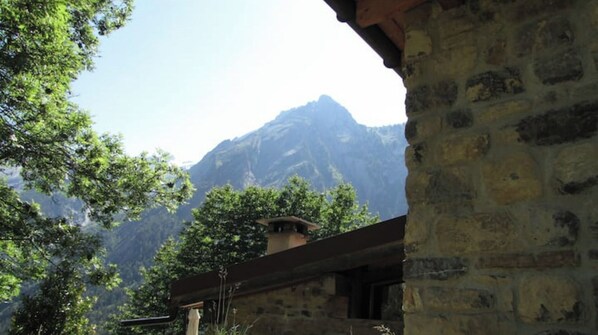 Ein Berg mit einem Steinhaus im Vordergrund.