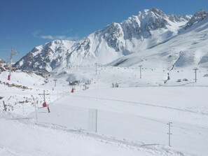 A snow-covered ski slope with ski lifts and a mountain backdrop.