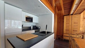 Una cocina moderna con gabinetes blancos, encimera negra y vigas de madera en el techo.