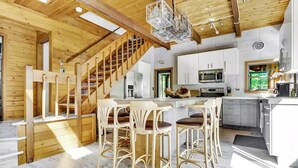 A spacious kitchen with white cabinets, a stainless steel microwave, and a large island with bar stools.