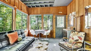 A cozy room with a leather sofa, a patterned armchair, a small table, and a dining table with chairs.